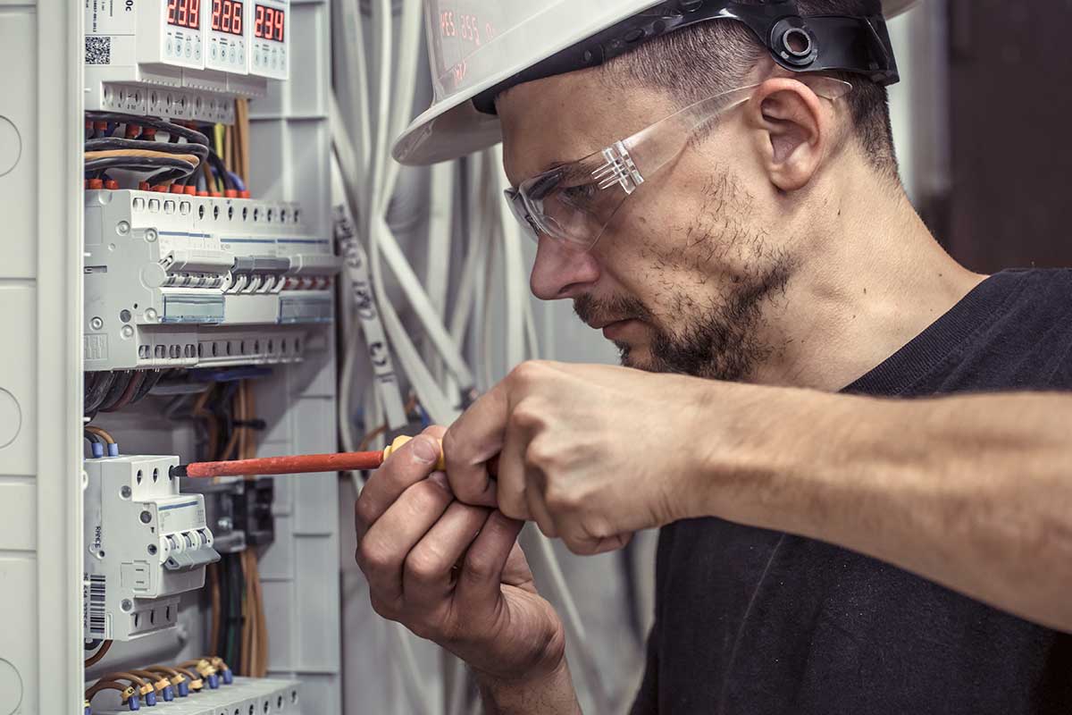 a-male-electrician-works-in-a-switchboard-with